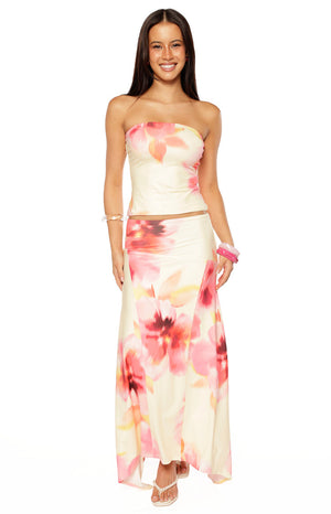 Our model wears a long flowing maxi-skirt in a creamy white fabric featuring a large pink and coral abstract floral print and a gently flared hemline.