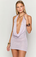 Blonde model wearing a purple glitter mini dress with a deep cowl neckline and halter neck