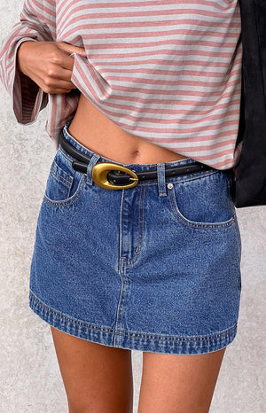 model wearing denim mini skirt with black belt with gold buckle and a red striped shirt