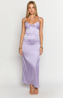blonde model wearing purple maxi dress, gold necklaces, gold bracelets posing with her and on a table with a candelabra