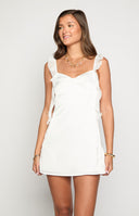 girl wearing a white satin mini dress with frill details paired with gold jewellery and a diamante handbag