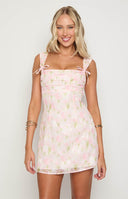 brunette model wearing  pink floral chiffon mini dress with ribbon details at the straps