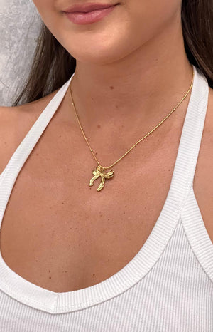 model is wearing a gold bow knot pendant necklace