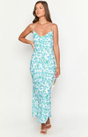 brunette model wearing a blue and green floral maxi dress styled with silver jewellery and white heels