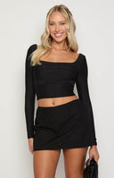 blonde girl wearing a black linen mini skort paired with a white crop top