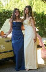Navy satin maxi dress with a straight neckline, thin spaghetti straps, and a flowing skirt