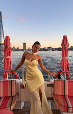 Yellow satin maxi dress with sweetheart neckline, thin spaghetti straps, a long neck scarf, and a sheer panel skirt with a hi