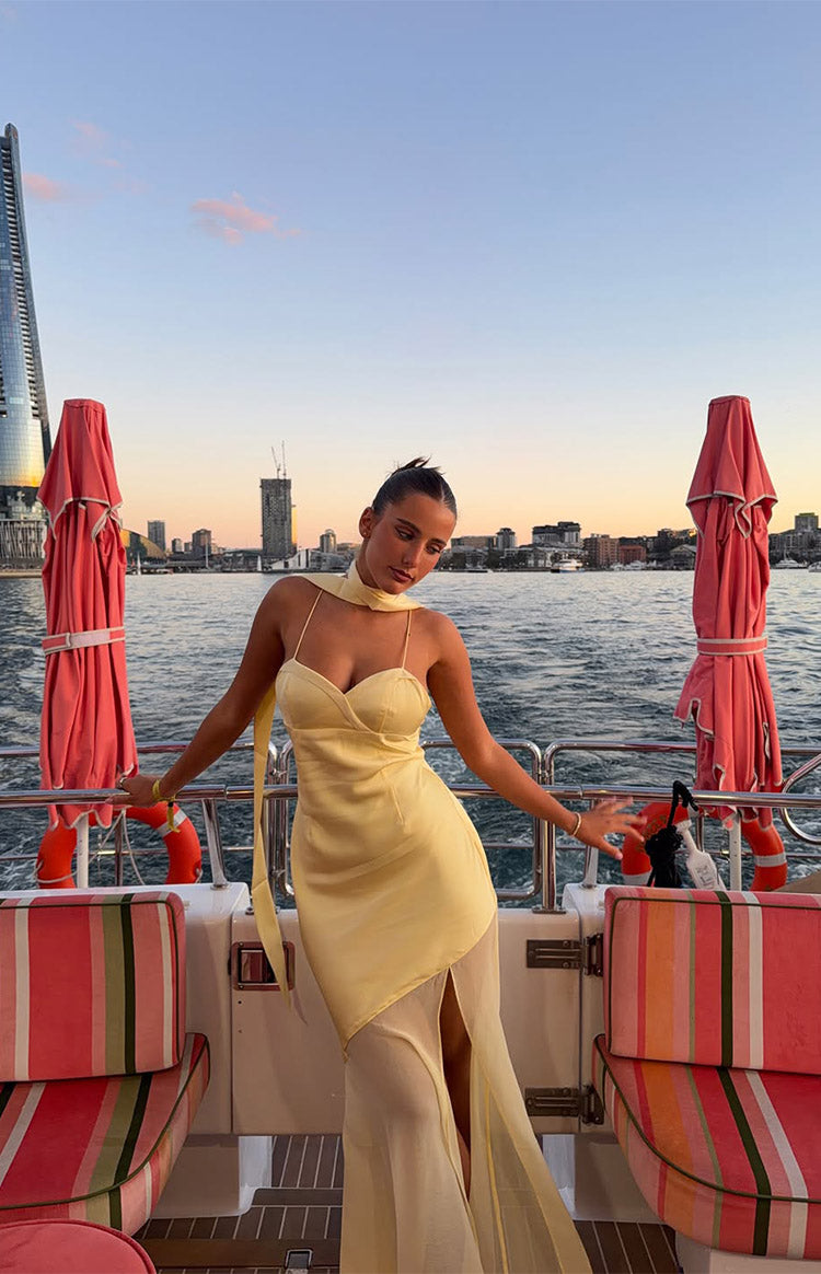 Yellow satin maxi dress with sweetheart neckline, thin spaghetti straps, a long neck scarf, and a sheer panel skirt with a hi