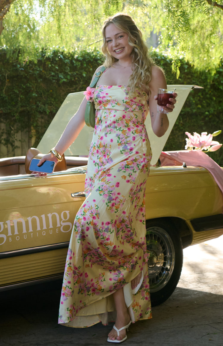 Full length view of a yellow satin maxi dress with a vibrant floral print, strapless neckline, and a flowy hem