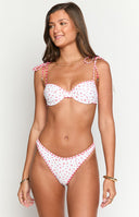 Model wearing a white bikini set with a red floral print and red gingham trim