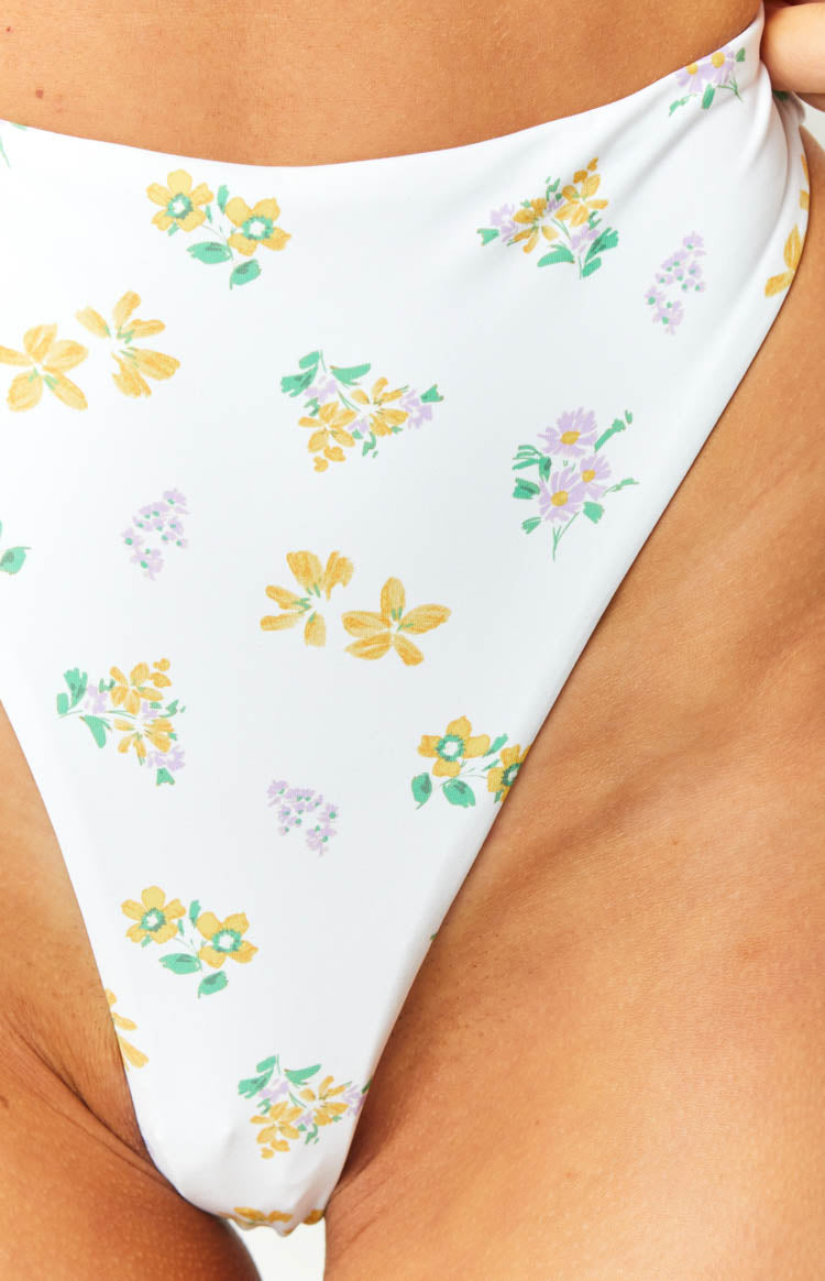 Close-up of the white bikini bottom with yellow and purple floral print and high-cut leg opening