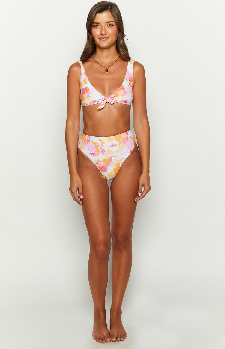 Front view of high-waisted bikini bottoms in a pink orange yellow wavy sun print, with a matching tie-front bikini top