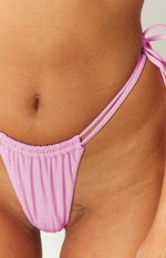 Side view showing the ruched top edge and double string ties of a pink bikini bottom