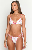 Girl wearing white triangle swim bottoms with an adjustable dual waist tie and red floral print design tied together with a red gingham trim