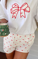 Side view of white cherry print pajama shorts and matching collared short sleeve button-up top