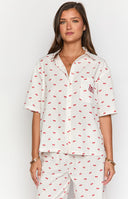 Girl wearing cherry print pajama set reading a book in bed.
