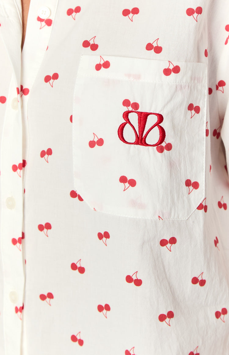 Close-up of the chest pocket on a white cherry print pajama shirt with a red embroidered BB design