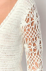 Close-up of the white crochet dress showing the tight knit bodice and open floral pattern on the long sleeve