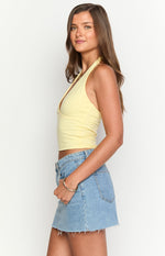 Side view of a yellow knit halter neck crop top with a deep V-neckline and fitted silhouette