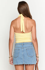 Rear view of a yellow fitted crop top showing the tie-back halter neck detail
