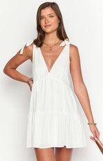 White mini dress with a deep V-neckline, tie-shoulder straps, and an empire waist leading to a tiered skirt