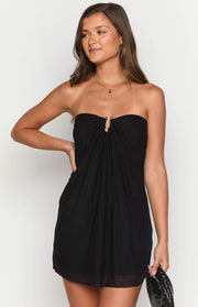 Close-up of the ruched strapless neckline with a gold ring detail on a black mini dress