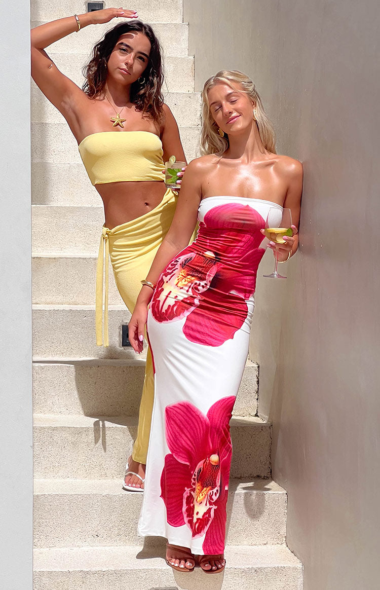 Full length view of the white strapless maxi dress with large red orchid print and ruched side detail