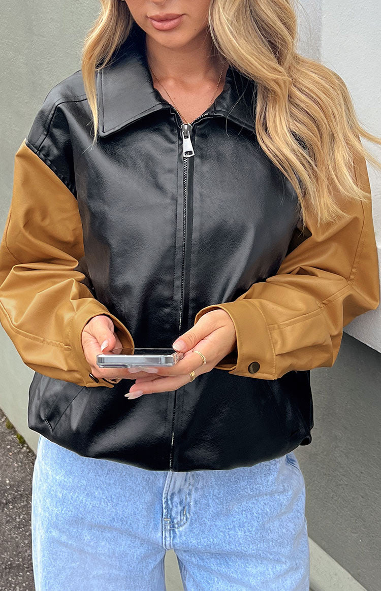 Close-up of the black and brown contrast bomber jacket with front zipper, collared neckline, and buttoned cuffs