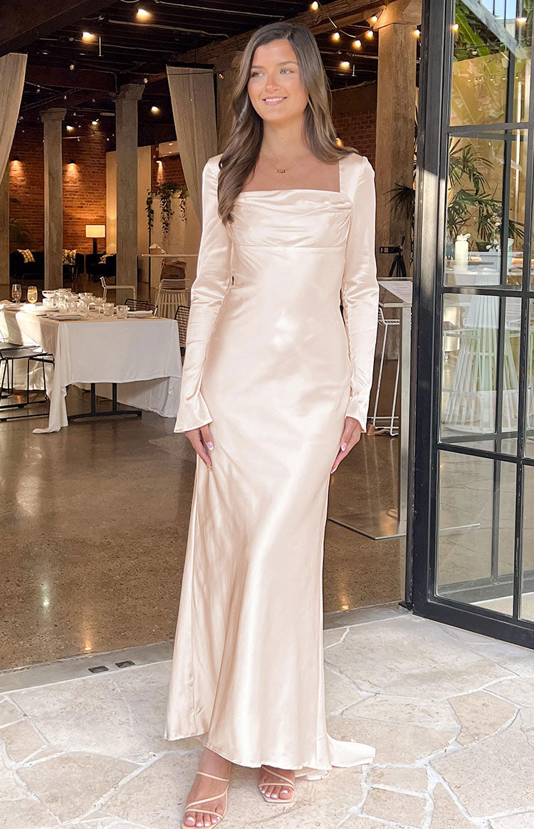 Close-up of the ruched detail at the square neckline and the long sleeve of a cream satin dress