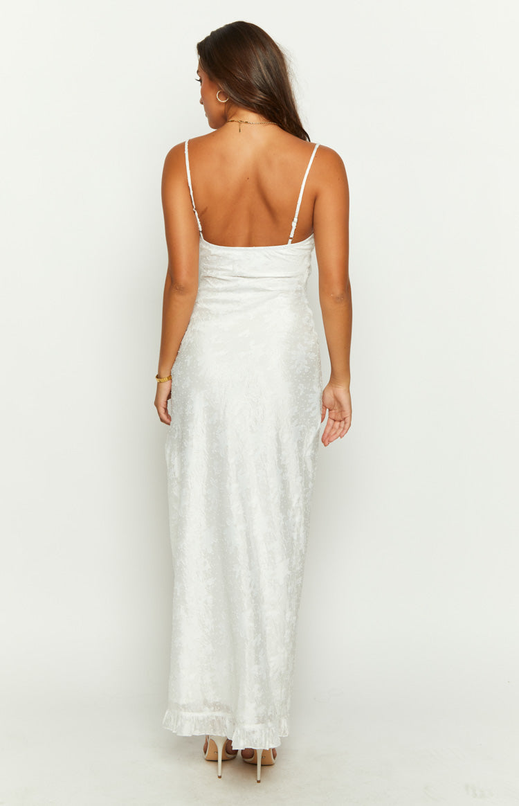 Rear view of the white maxi dress with thin spaghetti straps, a low scoop back, subtle textured fabric, and a ruffled hem