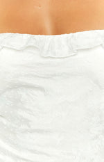 Close-up of the white maxi dress showing the ruffled neckline and textured fabric with subtle floral and swiss dot pattern
