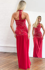 Rear view of a red halter maxi dress with a tied neck and intricate white and red beading on the bodice
