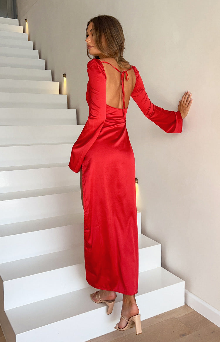 Rear view showing the low scoop back with tie detail and long wide-cuff sleeves of a red satin maxi dress