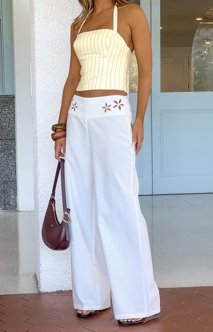 Front view of white wide-leg pants with intricate floral cutouts on the high waistband