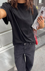 Angled view of the black plain tee, highlighting its crew neck, relaxed fit, and short sleeves