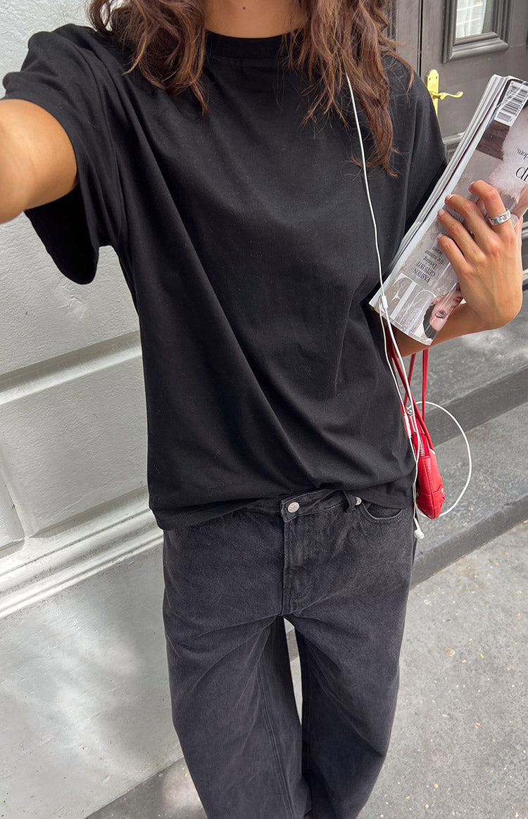 Angled view of the black plain tee, highlighting its crew neck, relaxed fit, and short sleeves