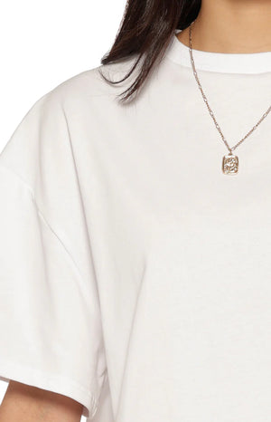 A lifestyle shot of our model wearing a loose oversized white t-shirt. This shirt features a classic crew neckline and drop-shoulder short sleeves.