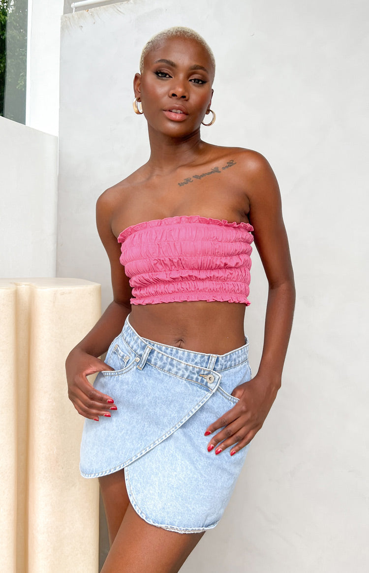 Asymmetrical light wash denim mini skirt with a wrap front, button closure, and front pockets