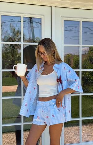 A woman wears a light blue and white striped pajama shirt with a red lobster print