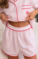 Pink and white striped pajama shorts with elasticated waist and red piping, matching button-up top with red piping