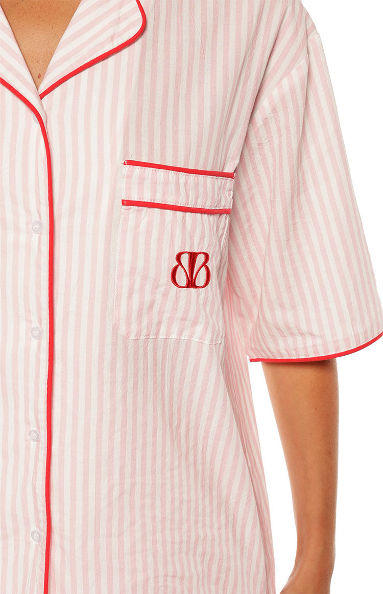 Close-up of the pink and white stripe pajama shirt showing the red embroidered logo on the chest pocket and red piping