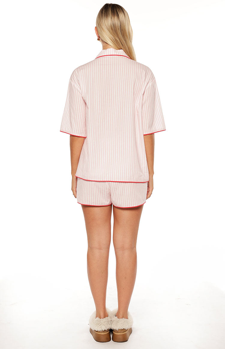 Rear view of pink and white striped pajama shorts and matching short sleeve top with red piping