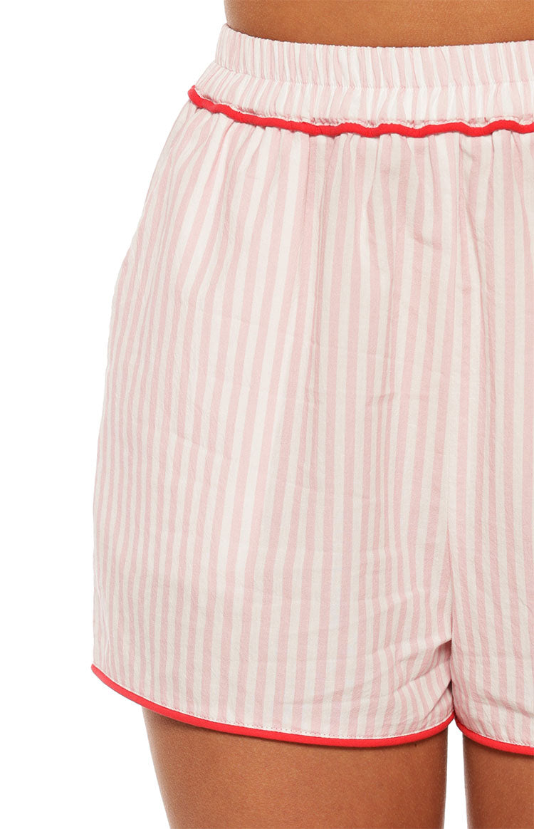 Close-up of the crinkled pink and white striped fabric with red piping on the elasticated waistband and hem