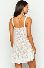Rear view of the white lace mini dress with a square back neckline, wide lace straps, and ruffled hem