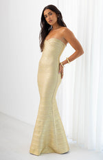 Side view of a gold strapless bandage maxi dress with a sweetheart neckline and flared mermaid hem