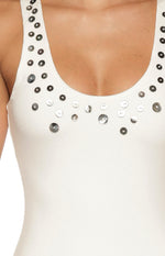 Detail shot of the white ribbed knit midi dress showing scattered silver and dark grey buttons on the scoop neckline