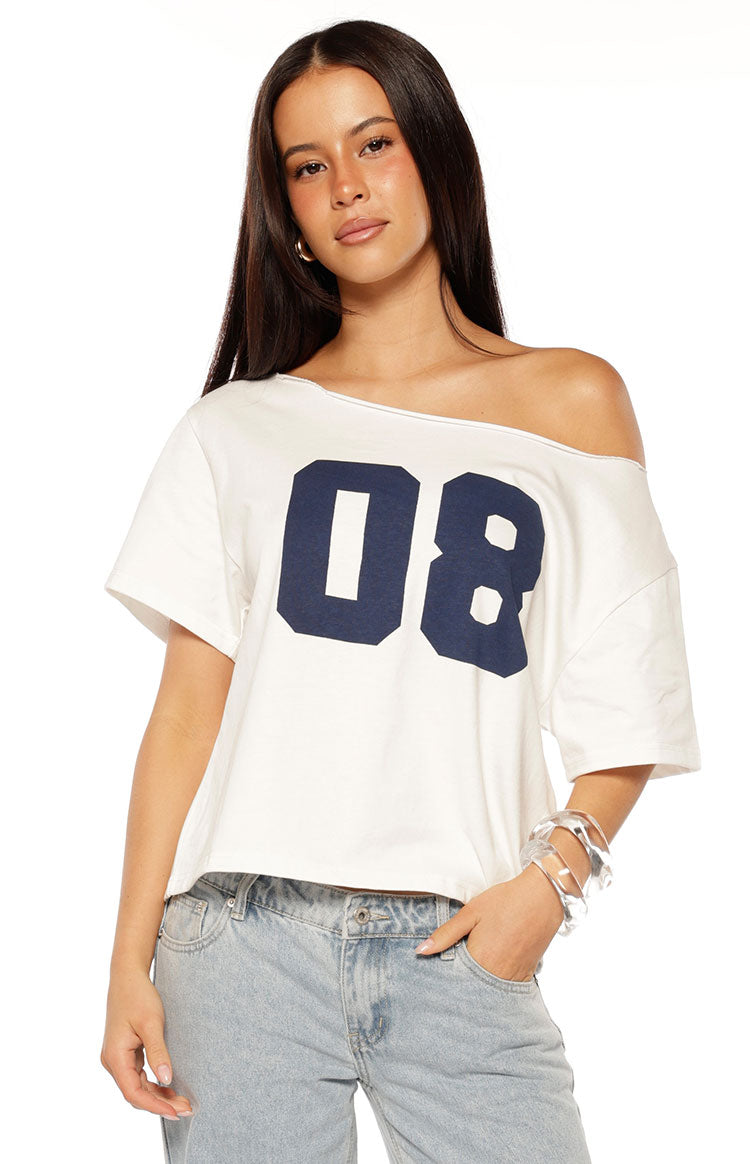 White oversized tee with a raw edge neckline worn off one shoulder and a navy '08' print