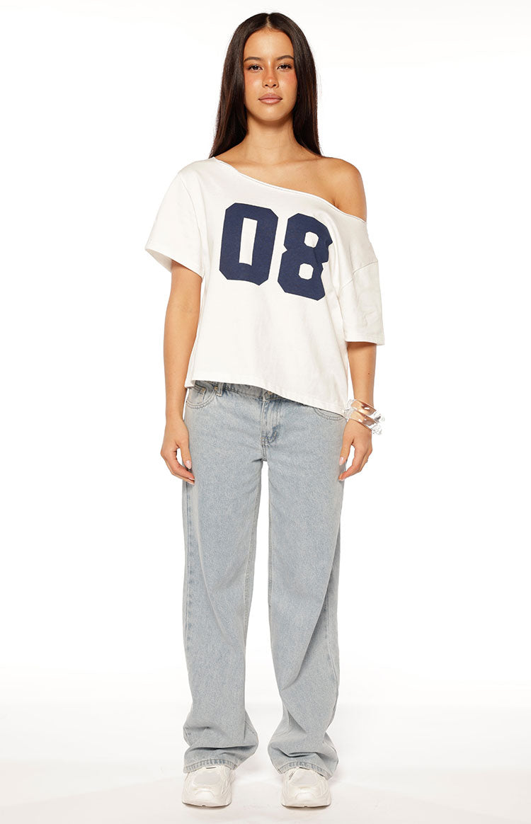 White oversized tee with navy "08" print, worn off one shoulder, showing the relaxed fit and cropped hem