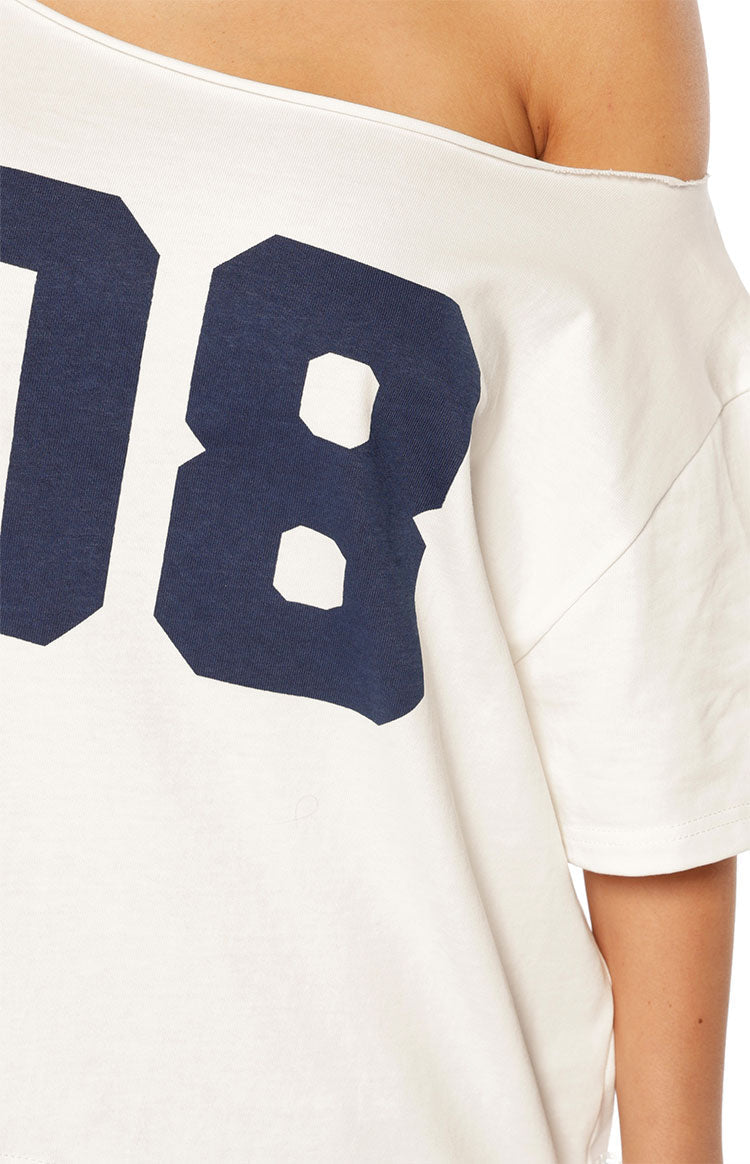 Close-up of the raw edge off-shoulder neckline and navy '18' print on a white oversized tee
