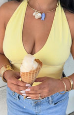 Close-up of the fitted yellow halter crop top featuring a deep V-neckline